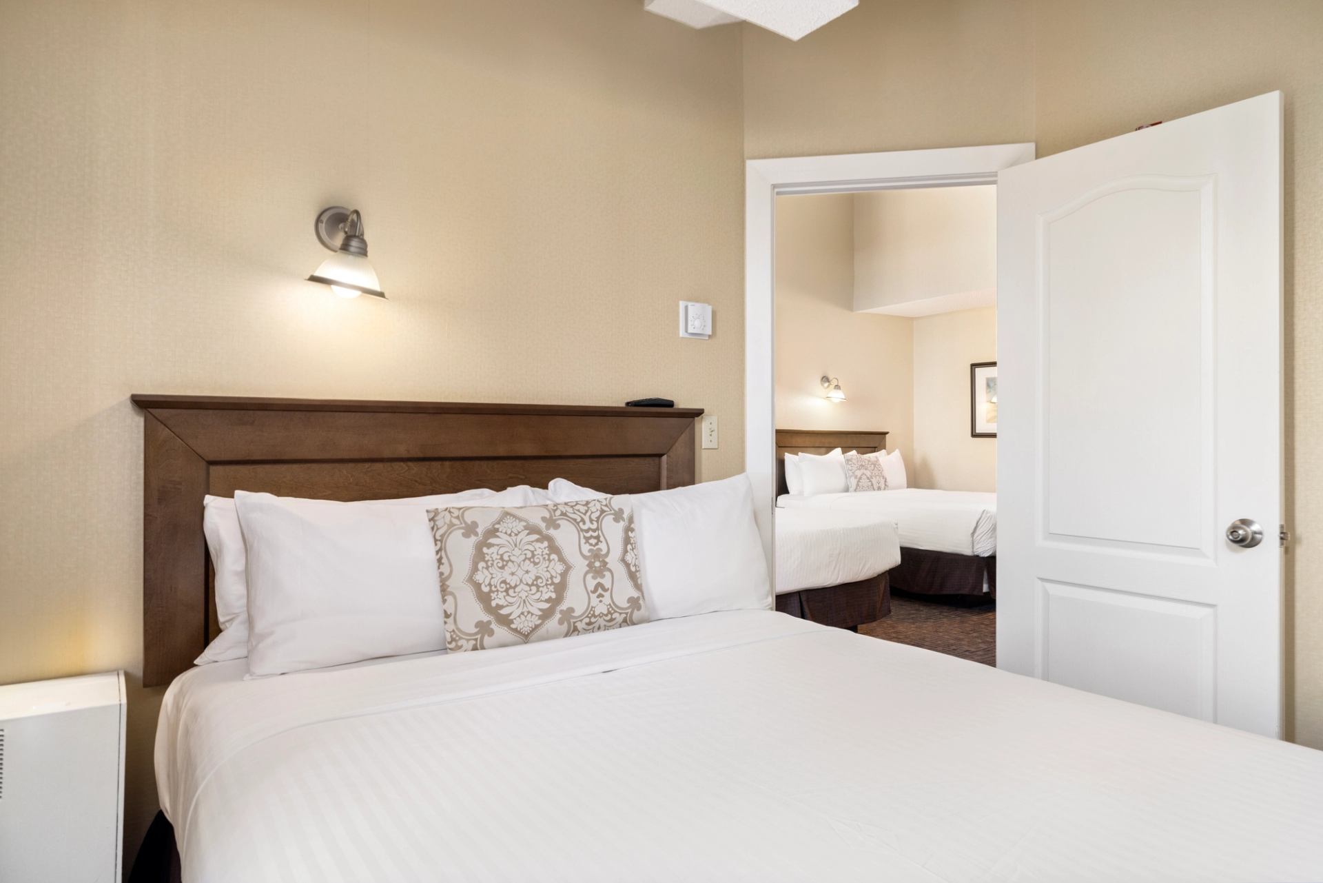 Hotel suite with two beds, warm lighting, and connecting room layout.