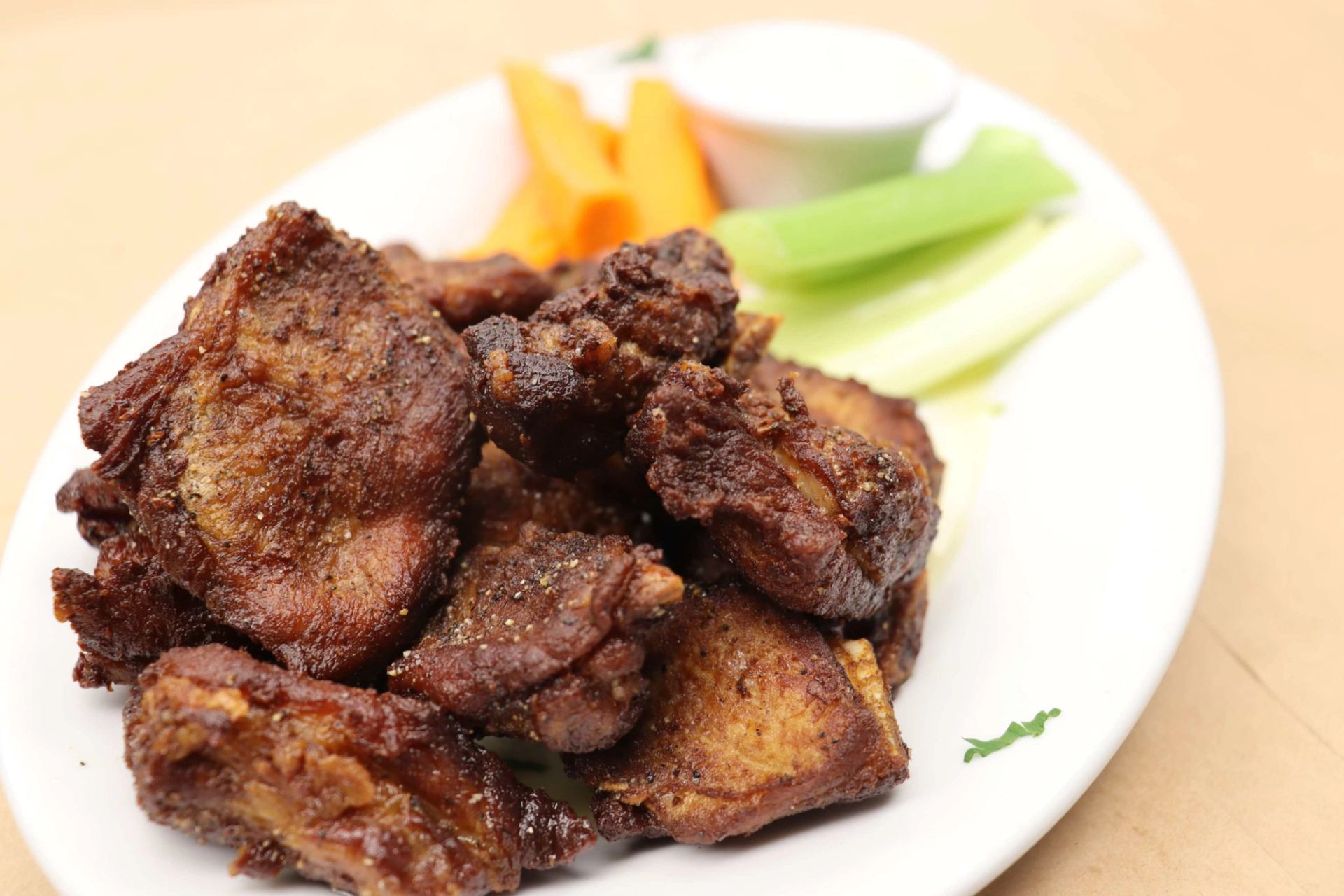 Plate of crispy fried chicken pieces served with celery, carrot sticks, and dipping sauce.