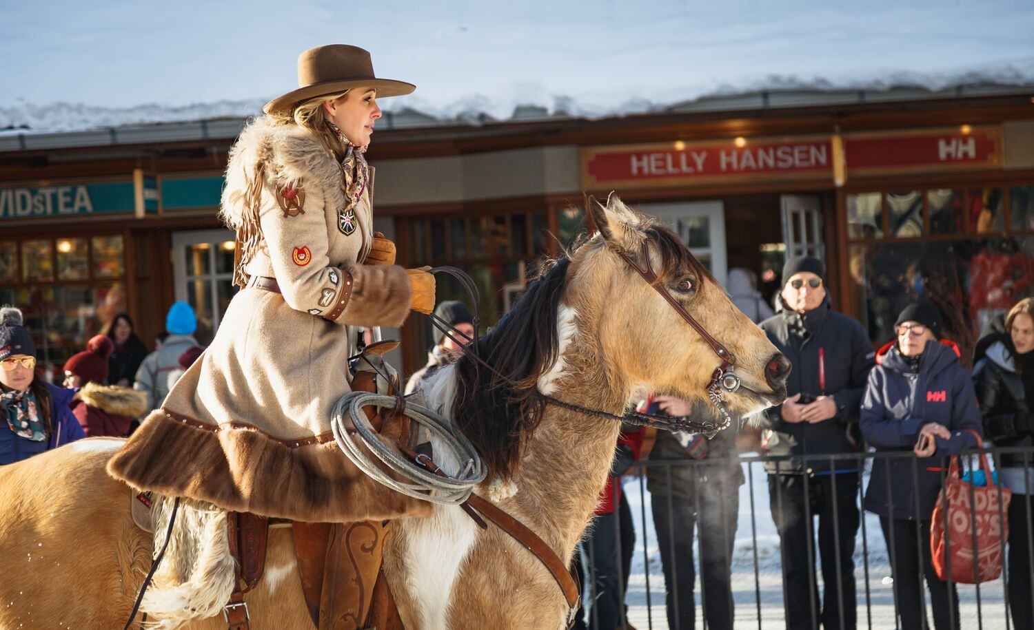 Horseback rider in winter attire passing storefronts during SnowDays Festival.