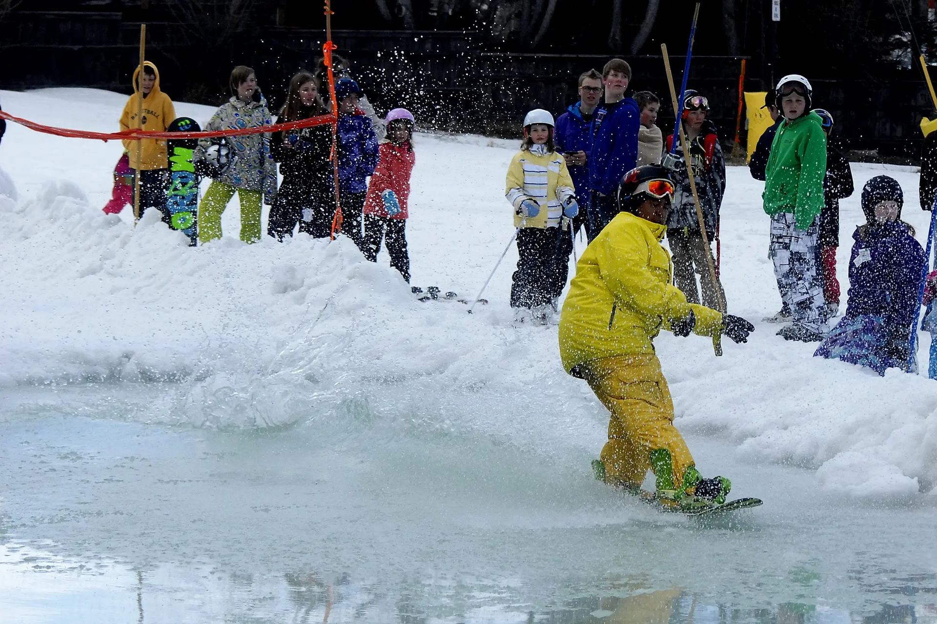 Snowboarder skims across a slush pool during spring event.