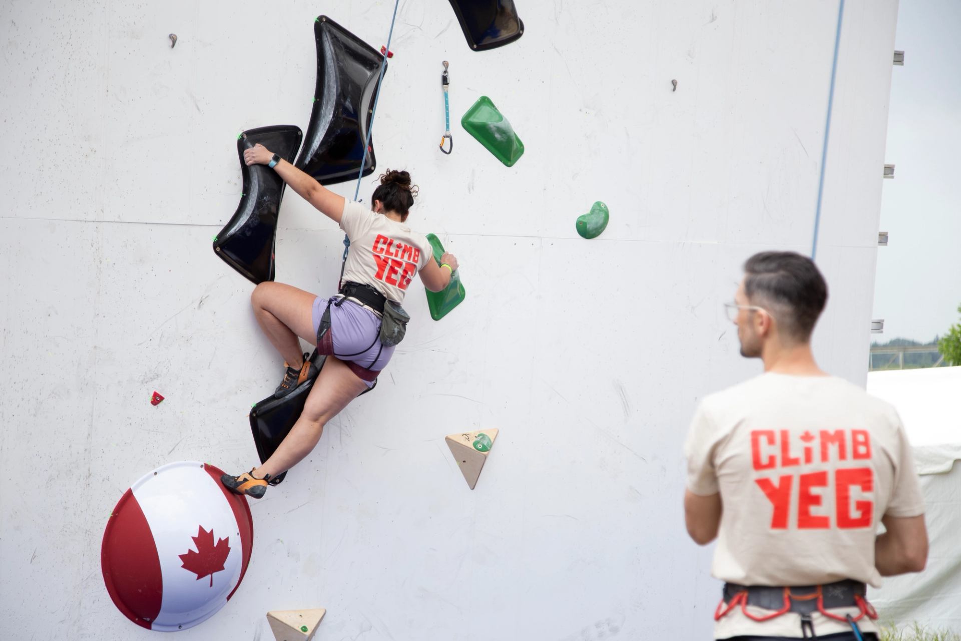 Climber on a wall with large holds and a Canadian beach ball at Climb YEG.
