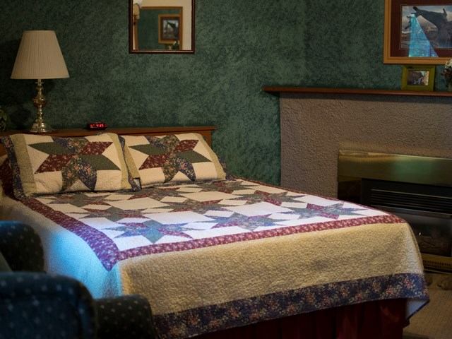 Cozy lodge room with star-pattern quilt, fireplace, and green walls.