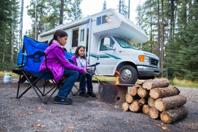 Children sitting by a campfire while RV camping at Whistlers Campground in Jasper National Park.