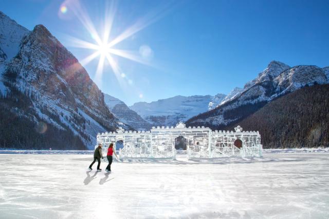 Couple skating on Lake Louise with ice sculpture in background.