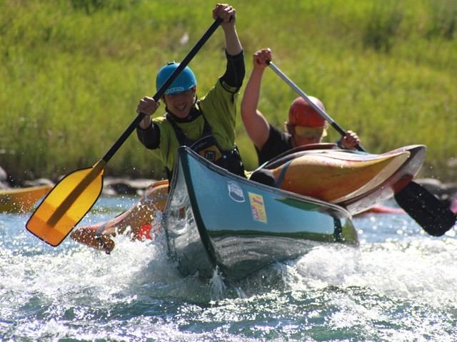 Two people paddling a canoe through fast-moving water.