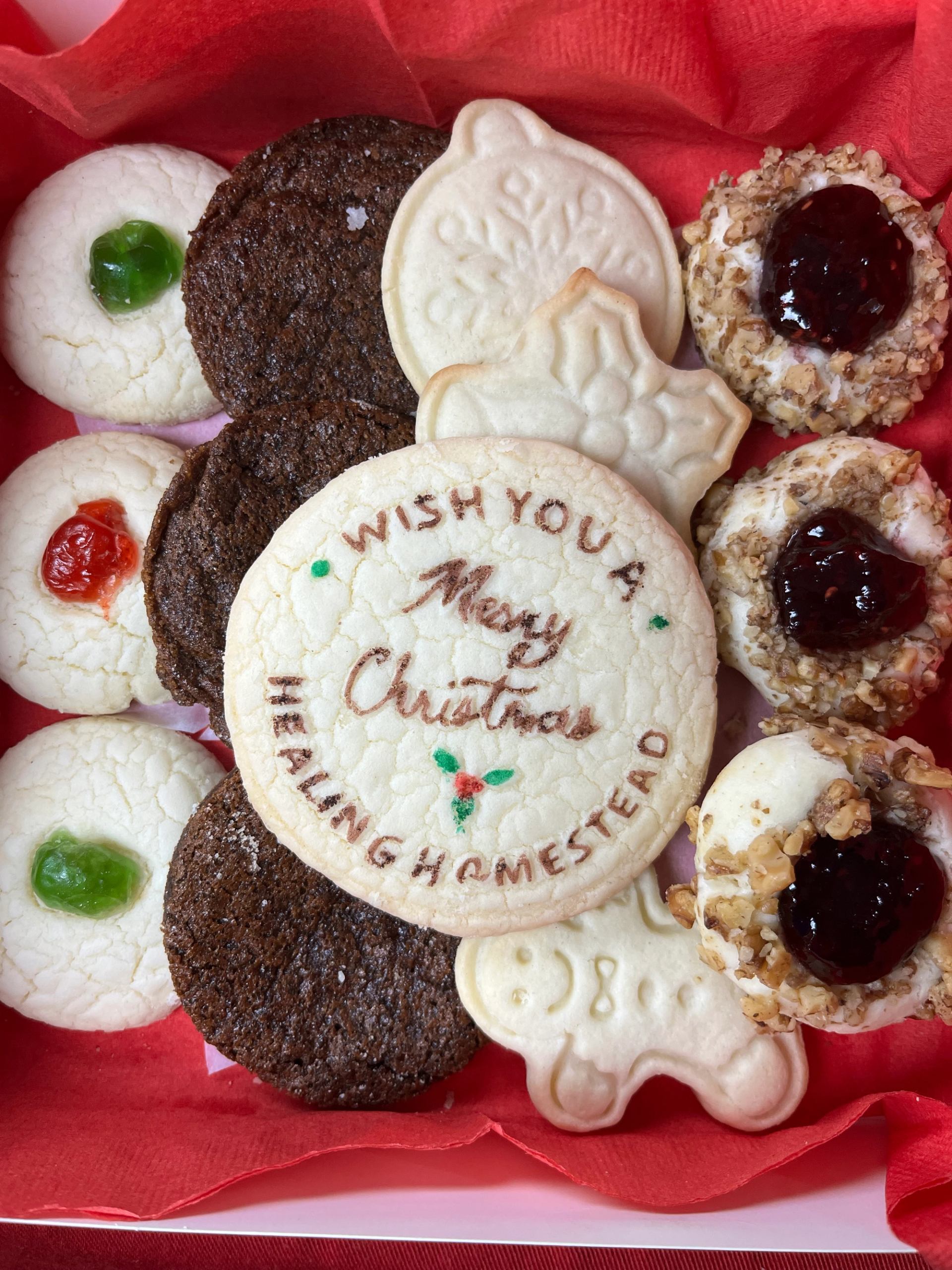 Assorted holiday cookies in a red box with a festive message.