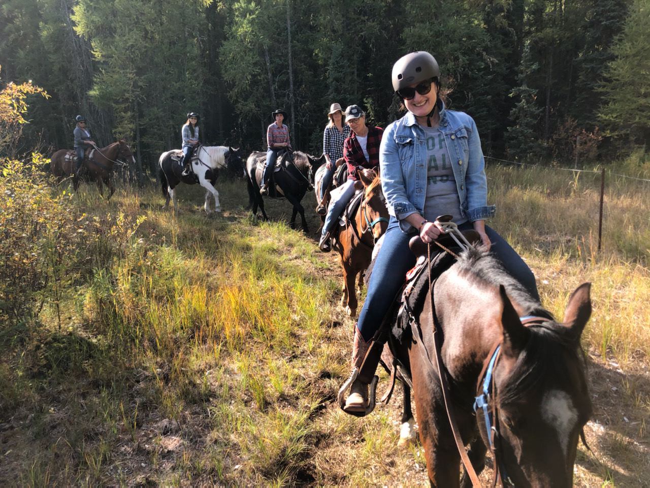 A group of women riding horses on the trail.