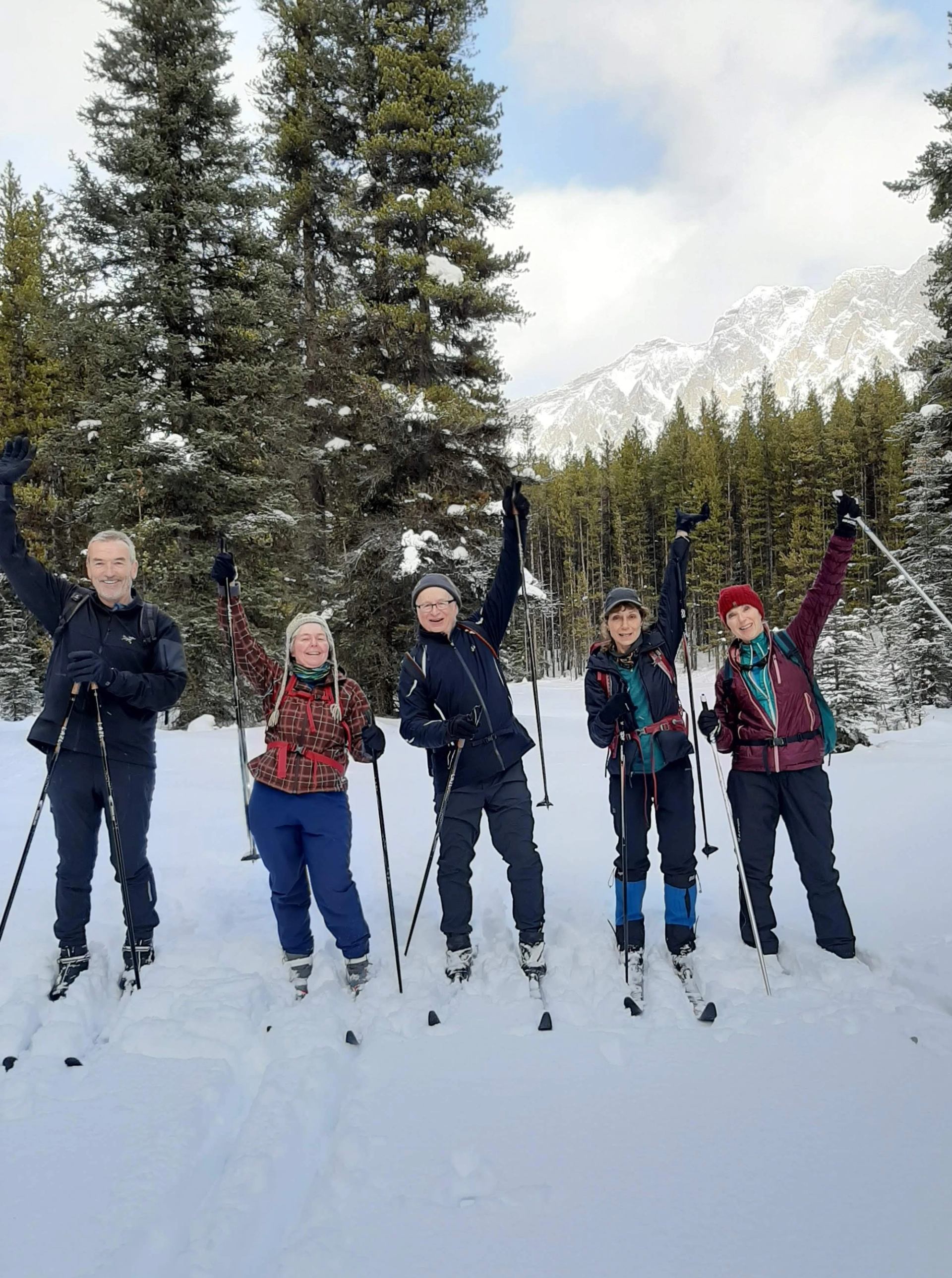 Group skiing through snowy forest during cross-country lesson.