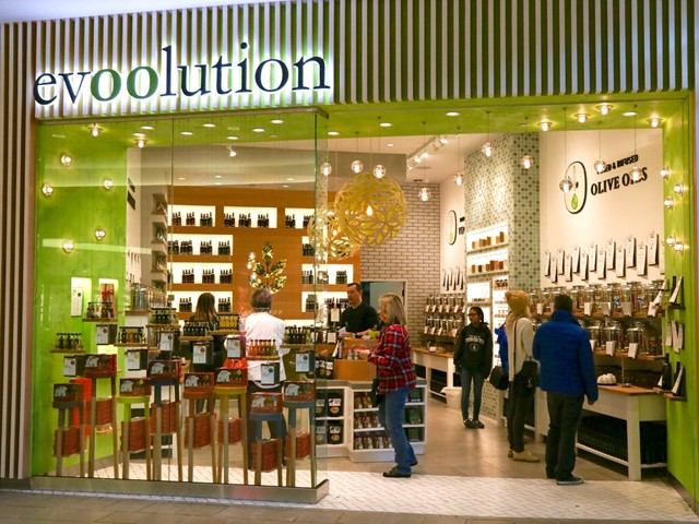 Modern olive oil shop with green signage and well-lit interior.