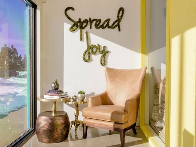 Gold chair beside window, small side table, and “Sheroad City” wall sign inside shop.