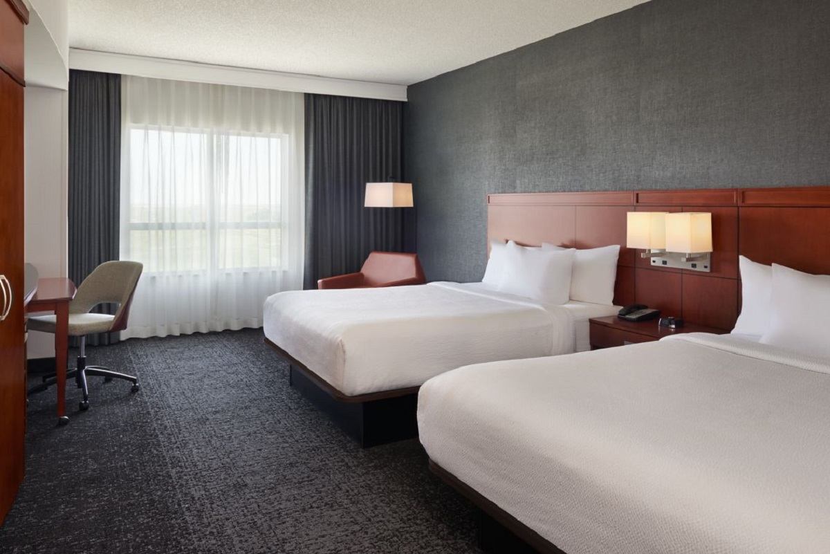 Hotel room with two queen beds, desk, and large window at Courtyard by Marriott Calgary Airport.