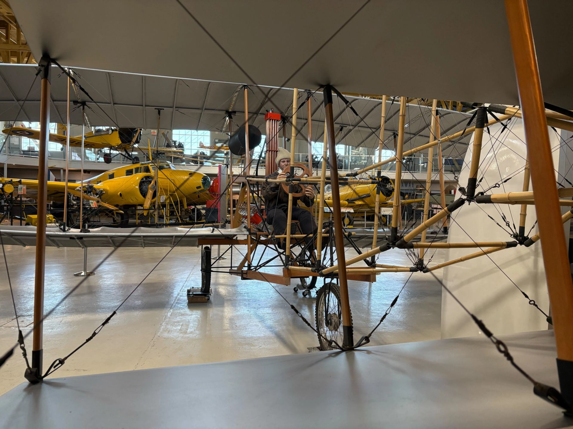 Early aircraft displayed inside an aviation museum, showing fabric wings and wooden framework.