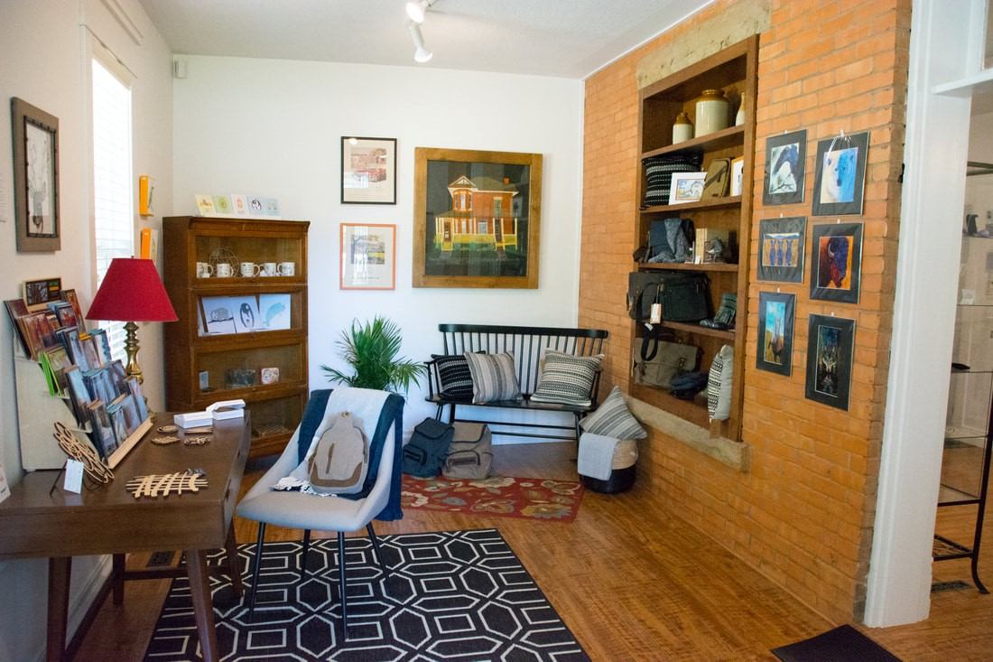 Boutique shop interior with display shelves, artwork on brick wall, and sofa seating.