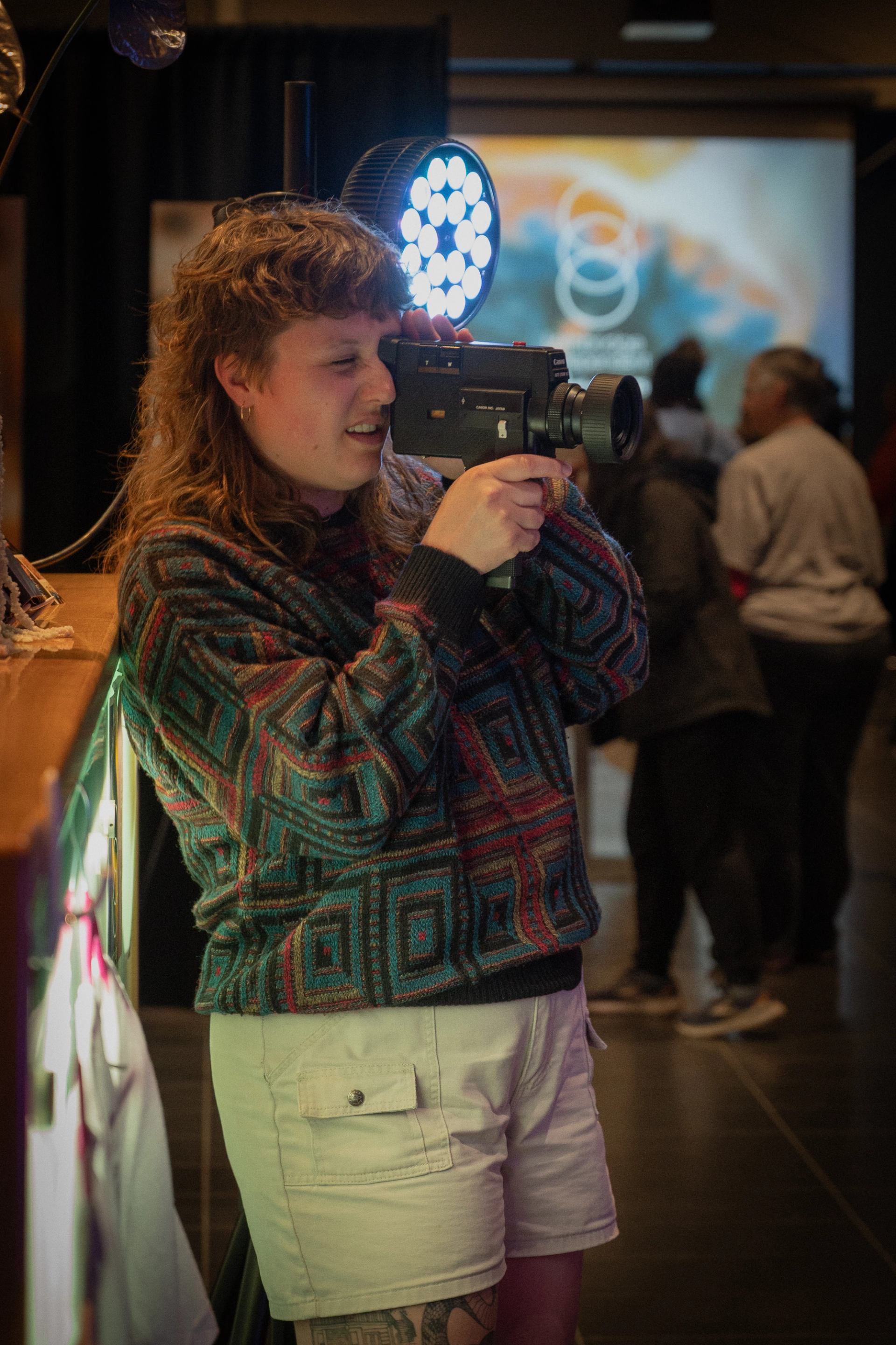Woman stands holding vintage 16mm film camera to eye, capturing a moment