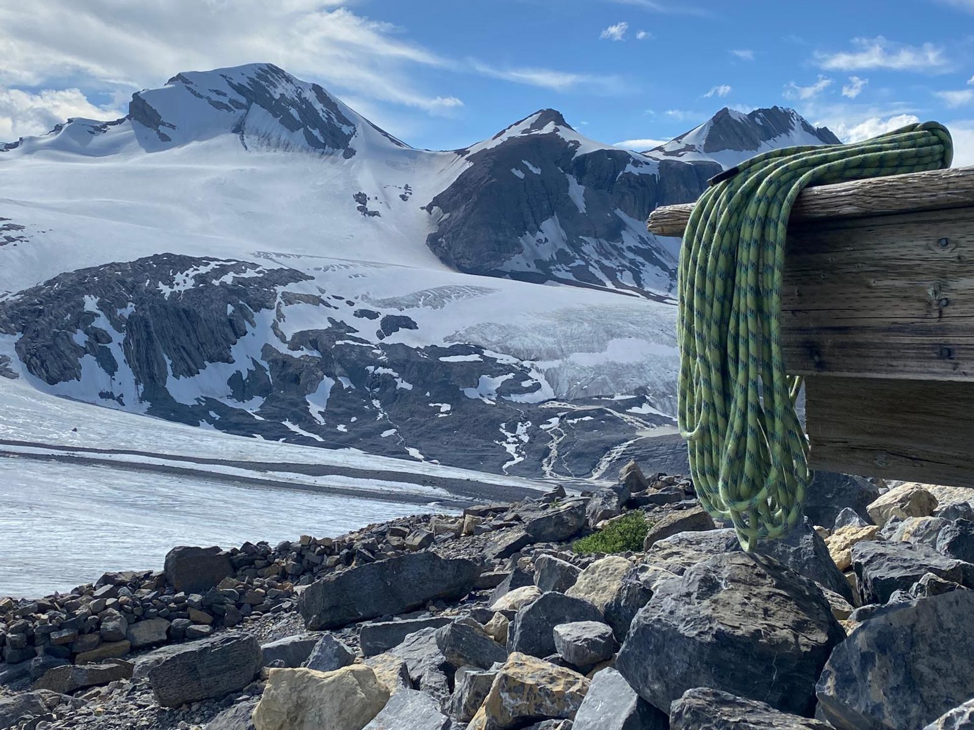 Climbing rope on wooden post with snowy mountain peaks in the background.
