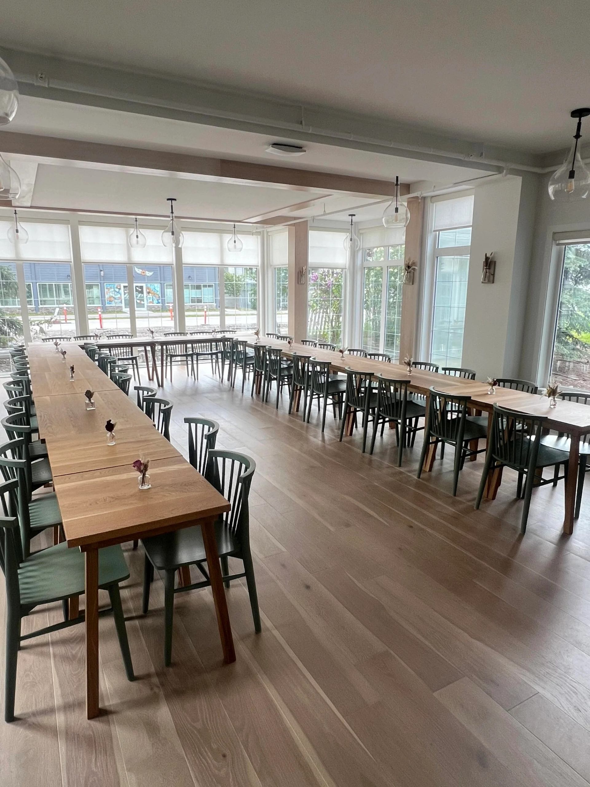 Long banquet tables arranged in a bright room with large windows