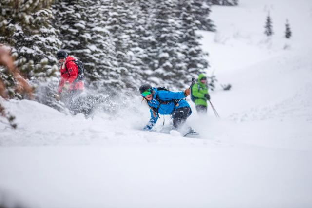 A ground level shot of an oncoming snowboarder, others in the background, at Castle Mountain Resort