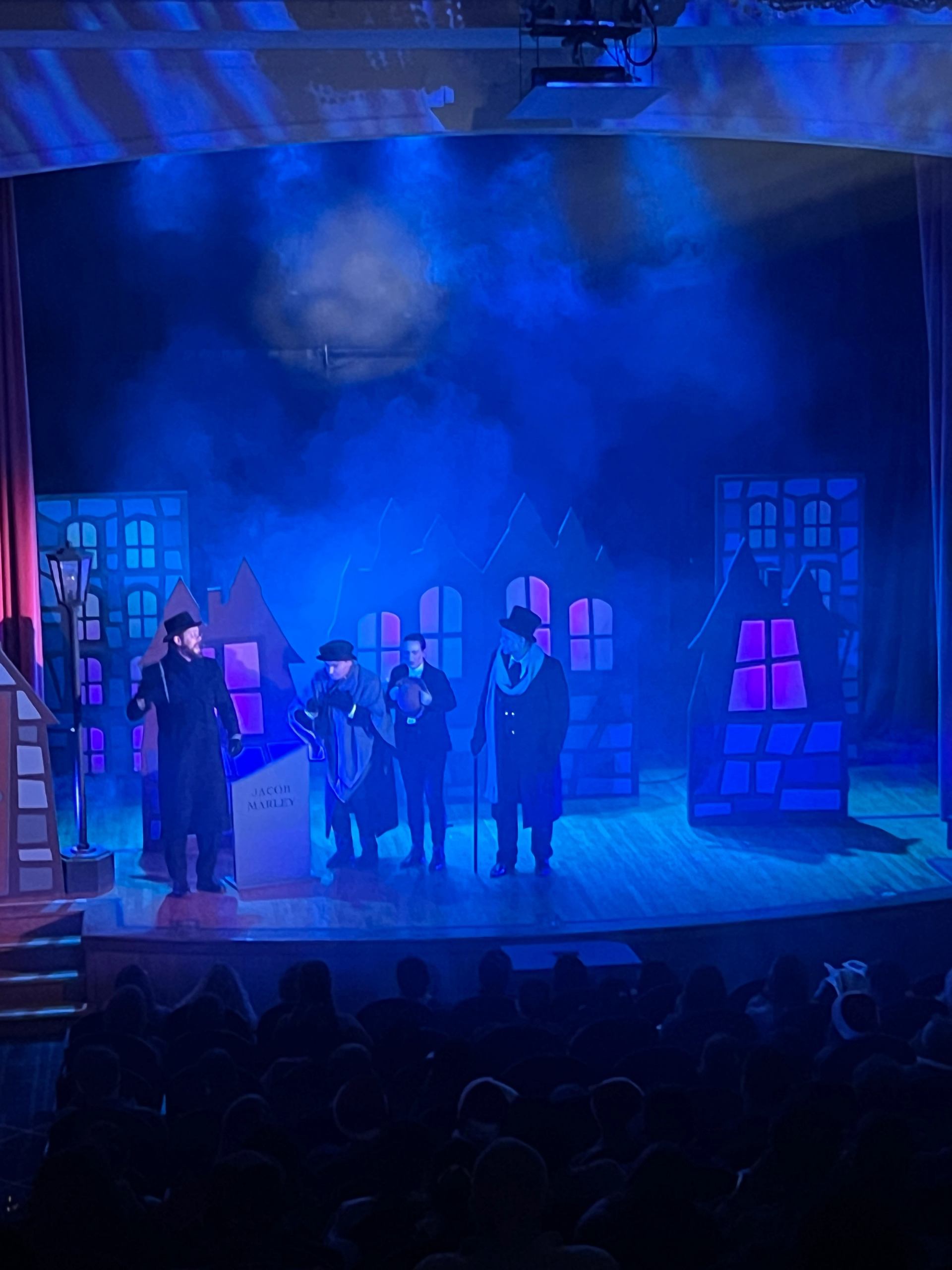 Actors perform with a glowing village background.