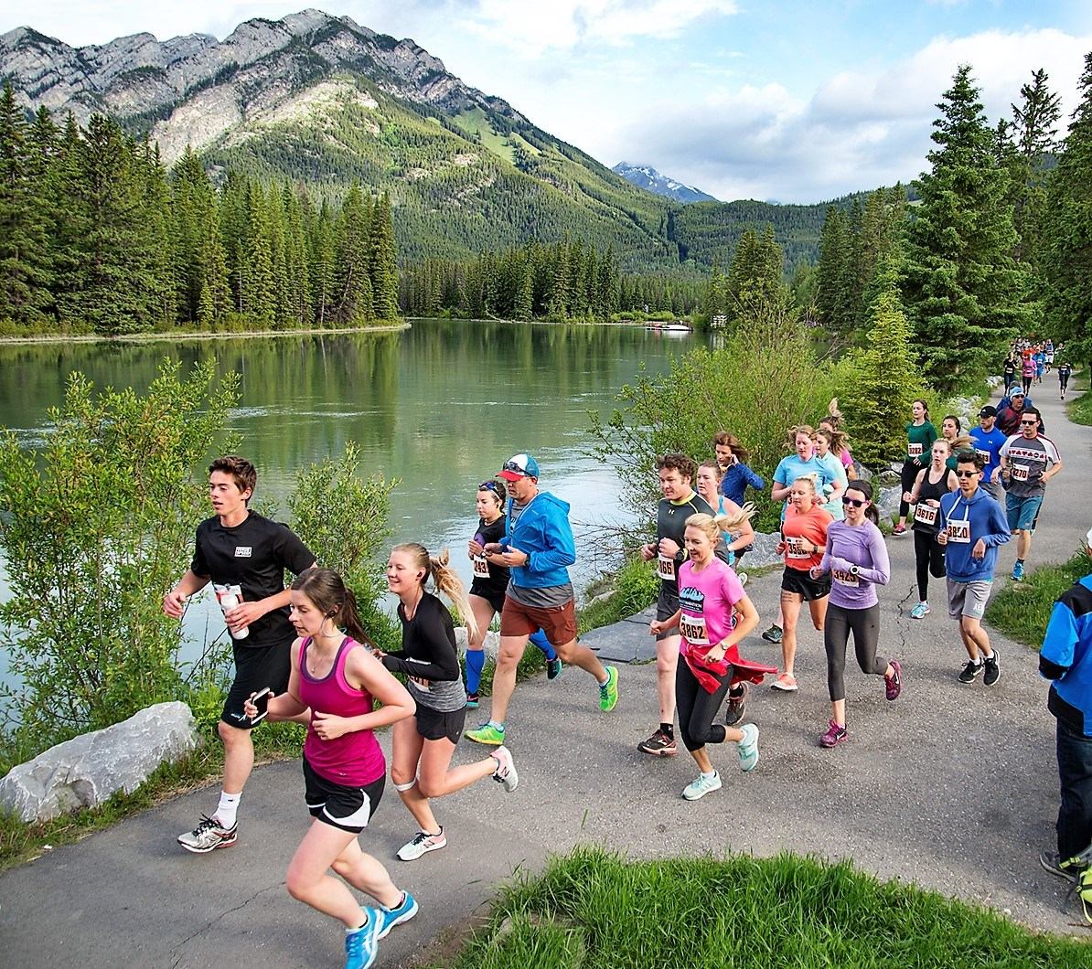 Group runs beside lake in scenic mountain setting.