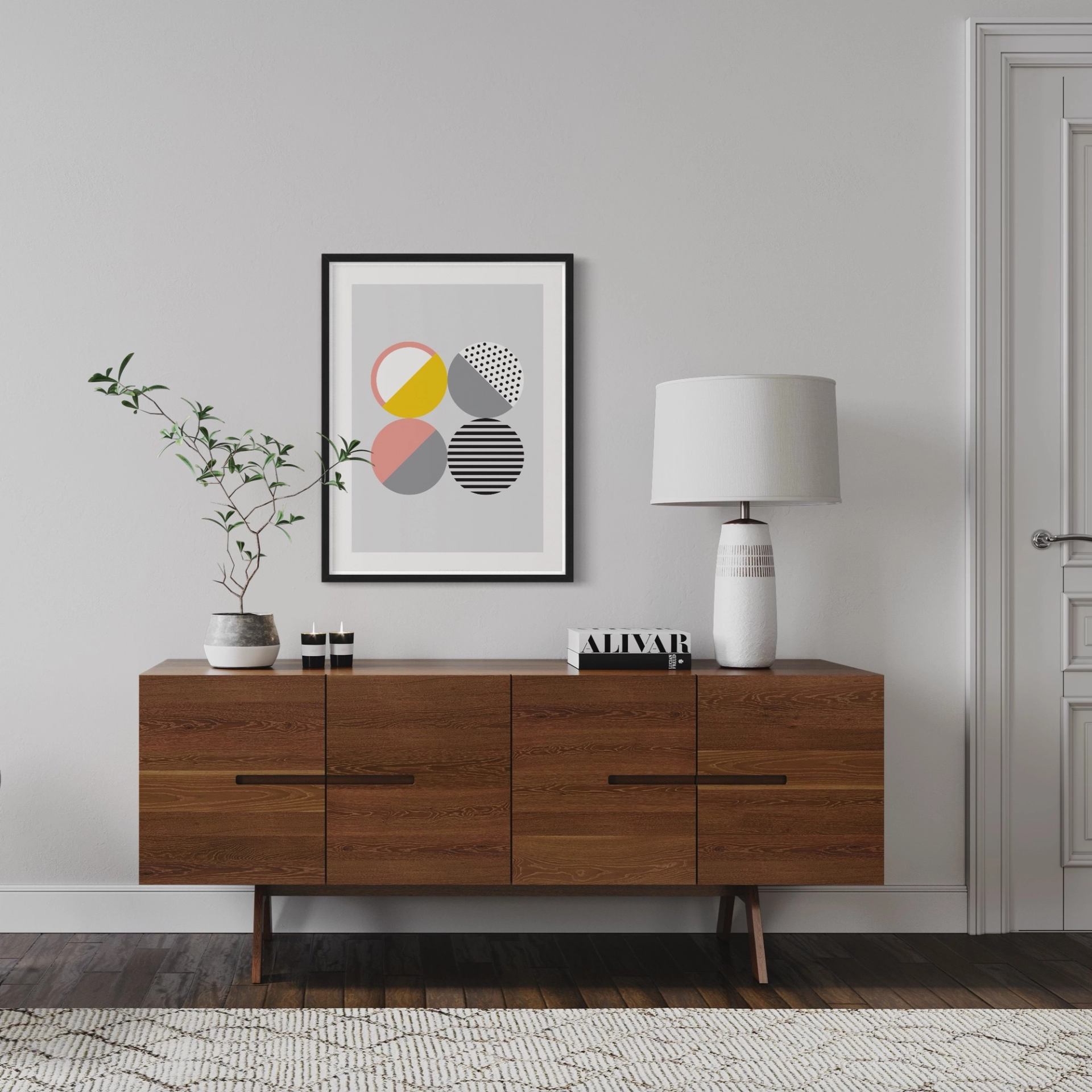 Wooden sideboard with a potted plant, table lamp and framed geometric print.