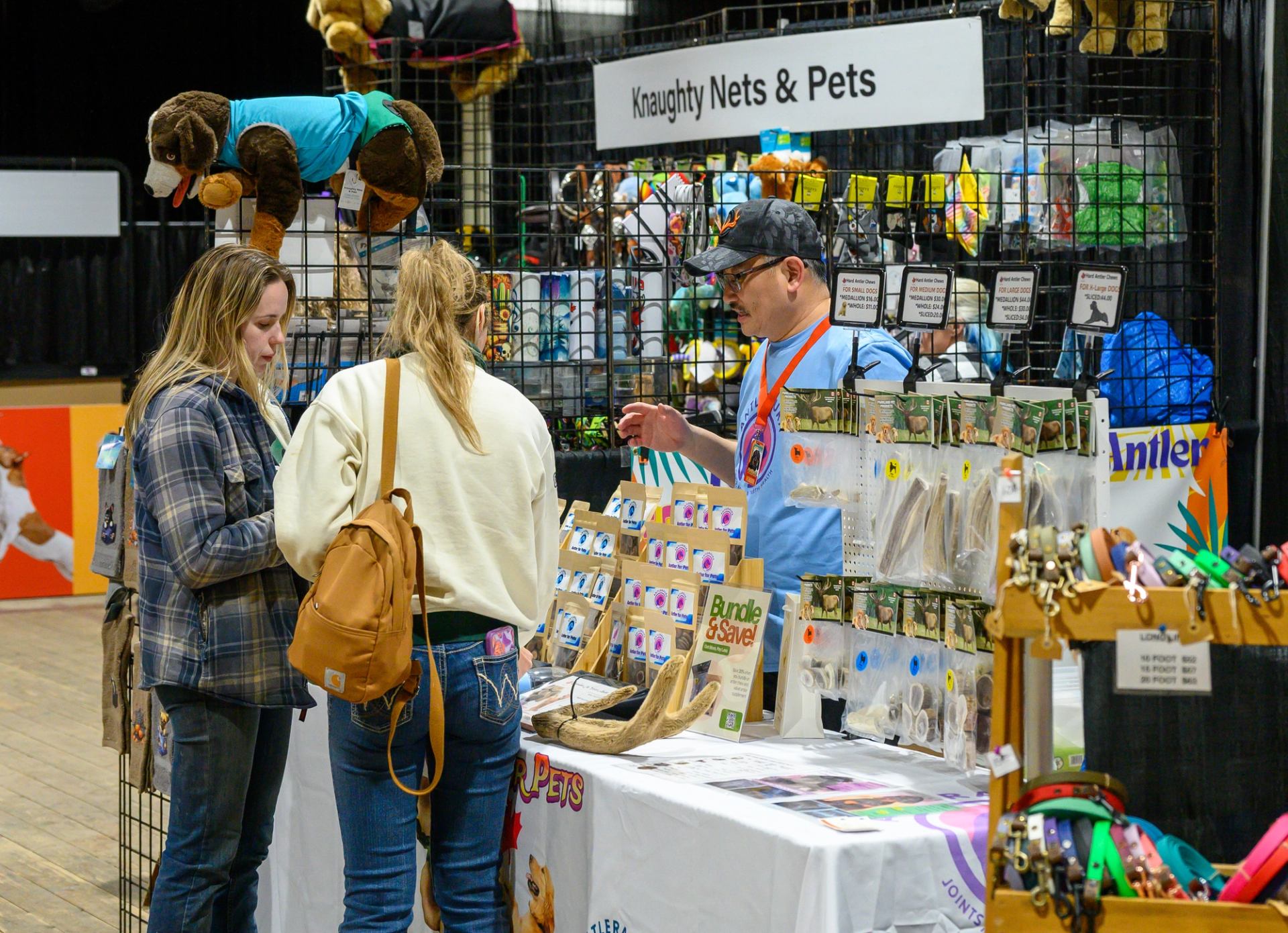 Vendor booth displaying pet accessories and treats while guests browse the table.
