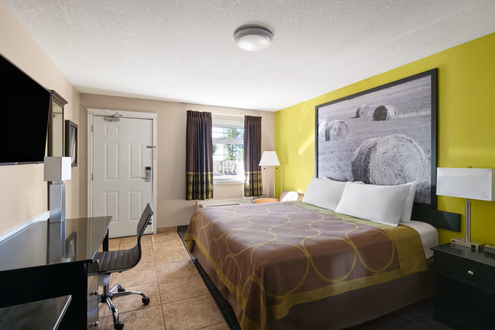 Super 8 by Wyndham Fort McMurray features a king guest room with a work desk, TV, and bright décor.