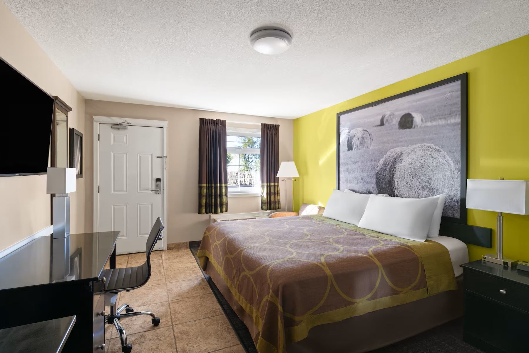 Super 8 by Wyndham Fort McMurray features a king guest room with a work desk, TV, and bright décor.