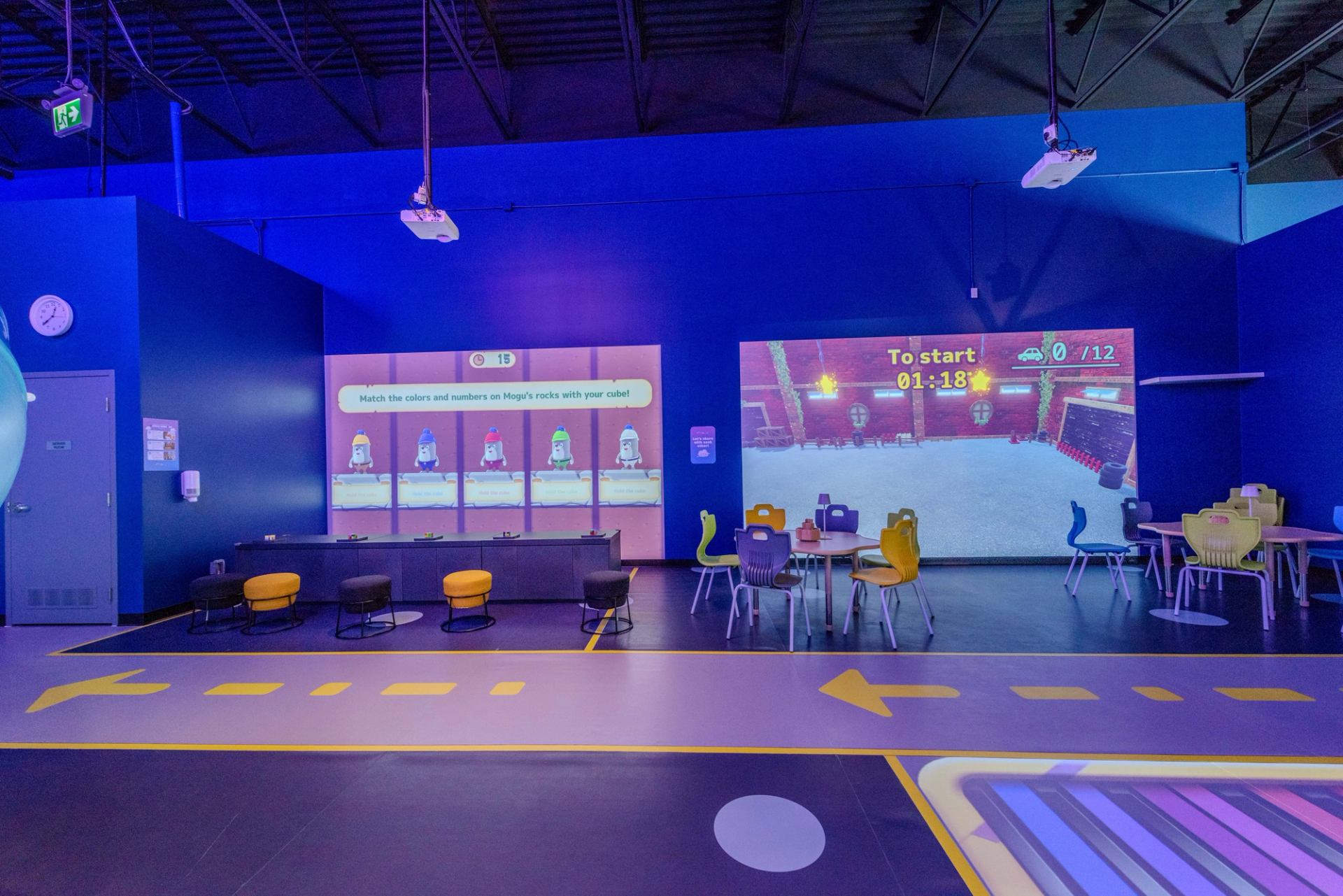 Interactive gaming area with large projection screens and colorful chairs at Cloud Land.