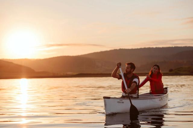 Couple canoeing on Cypress Lake at sunrise.