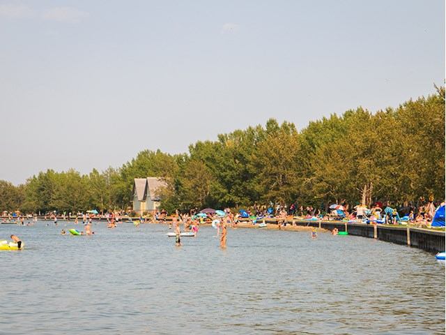 People swimming and relaxing by the Sylvan Lake boardwalk on a sunny day.