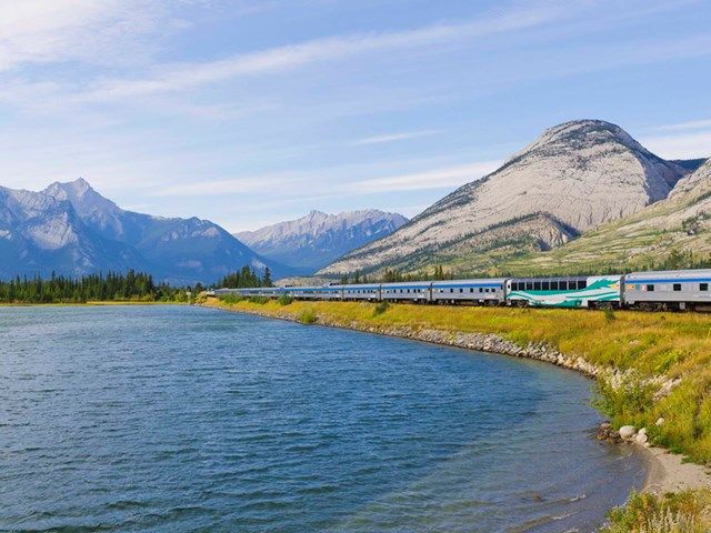 Via Rail train with mountains in the background.