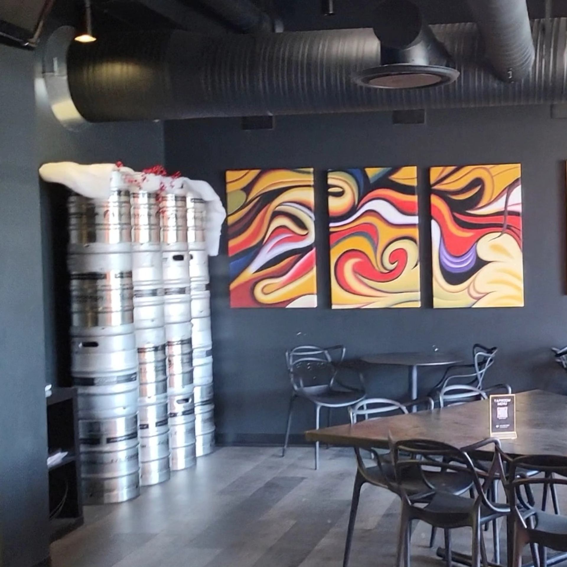 Modern brewery corner with stacked kegs and vibrant abstract wall art.