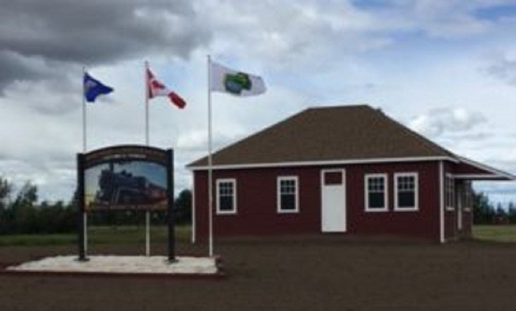 Red building with flags and a steam train sign at campground entrance.
