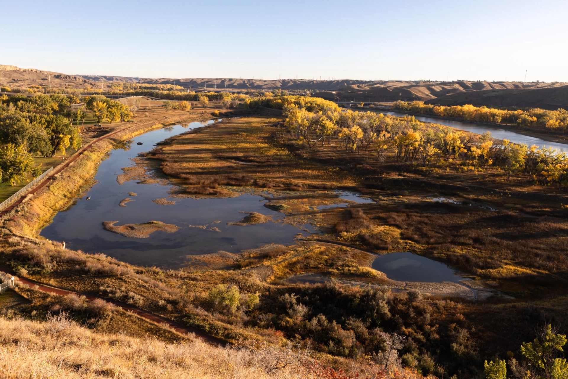 Wide river winding through brown and yellow wetlands, with distant low hills.