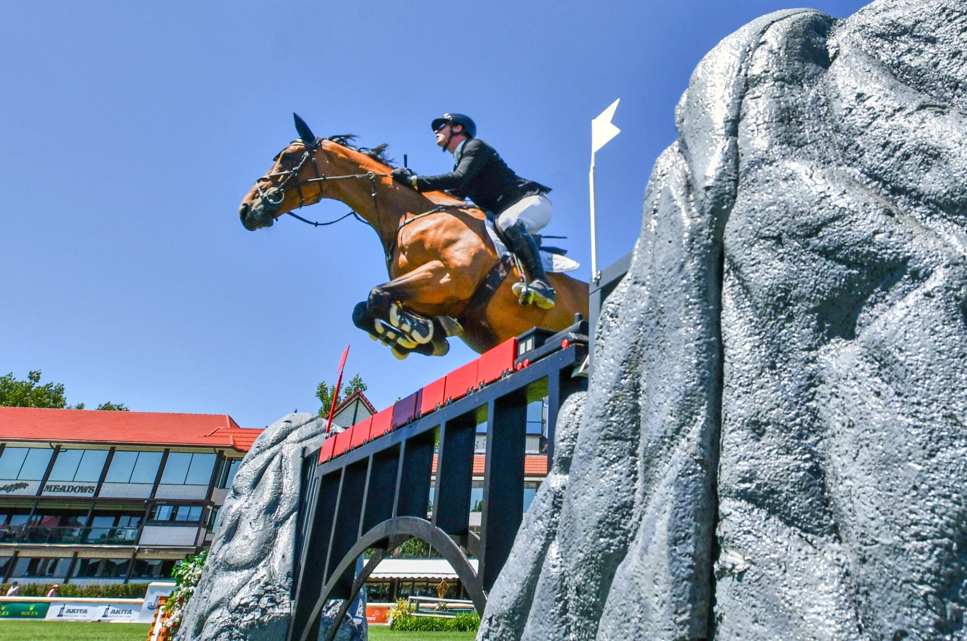Horse and rider leaping over an obstacle at an outdoor show‑jumping arena