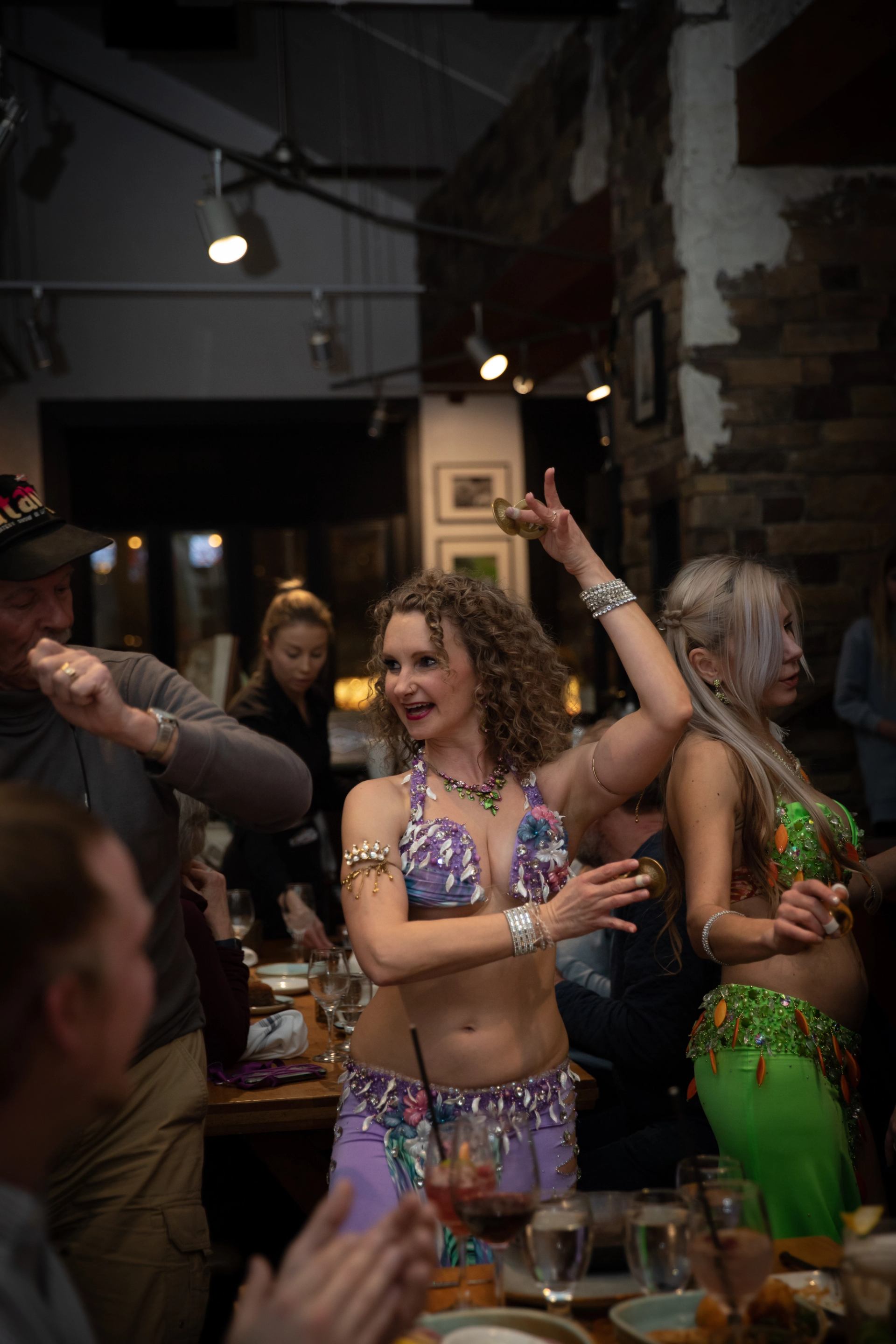 A belly dancer in costume dances table side during Greek night