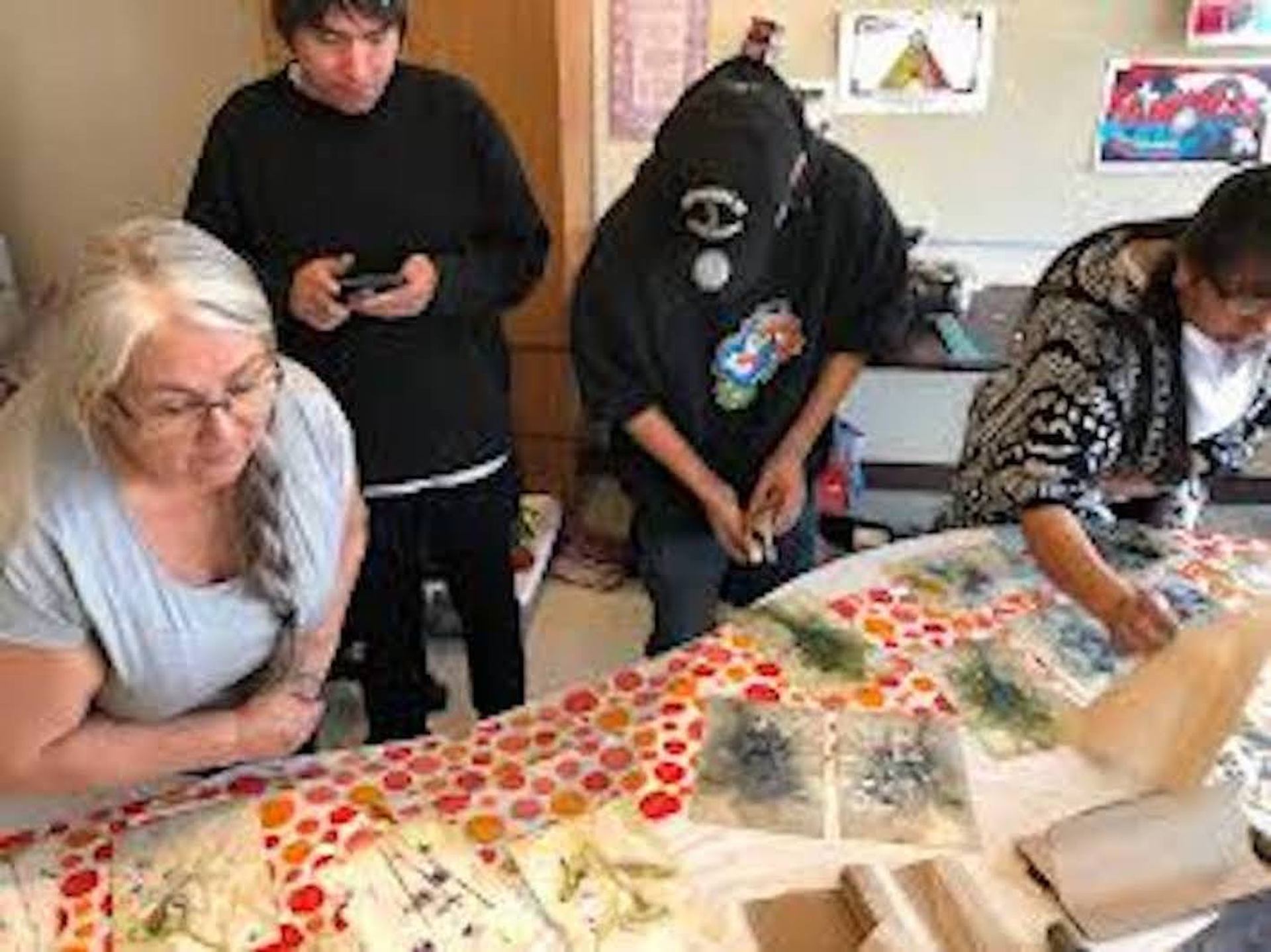 Participants arranging leaves and fabric for eco dyeing on a colorful workshop table.