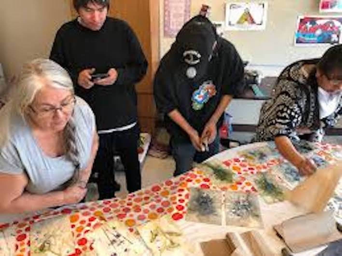 Participants arranging leaves and fabric for eco dyeing on a colorful workshop table.