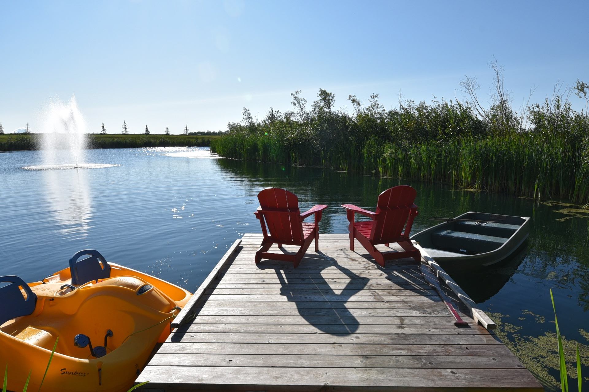 Two red chairs at the end of the dock.