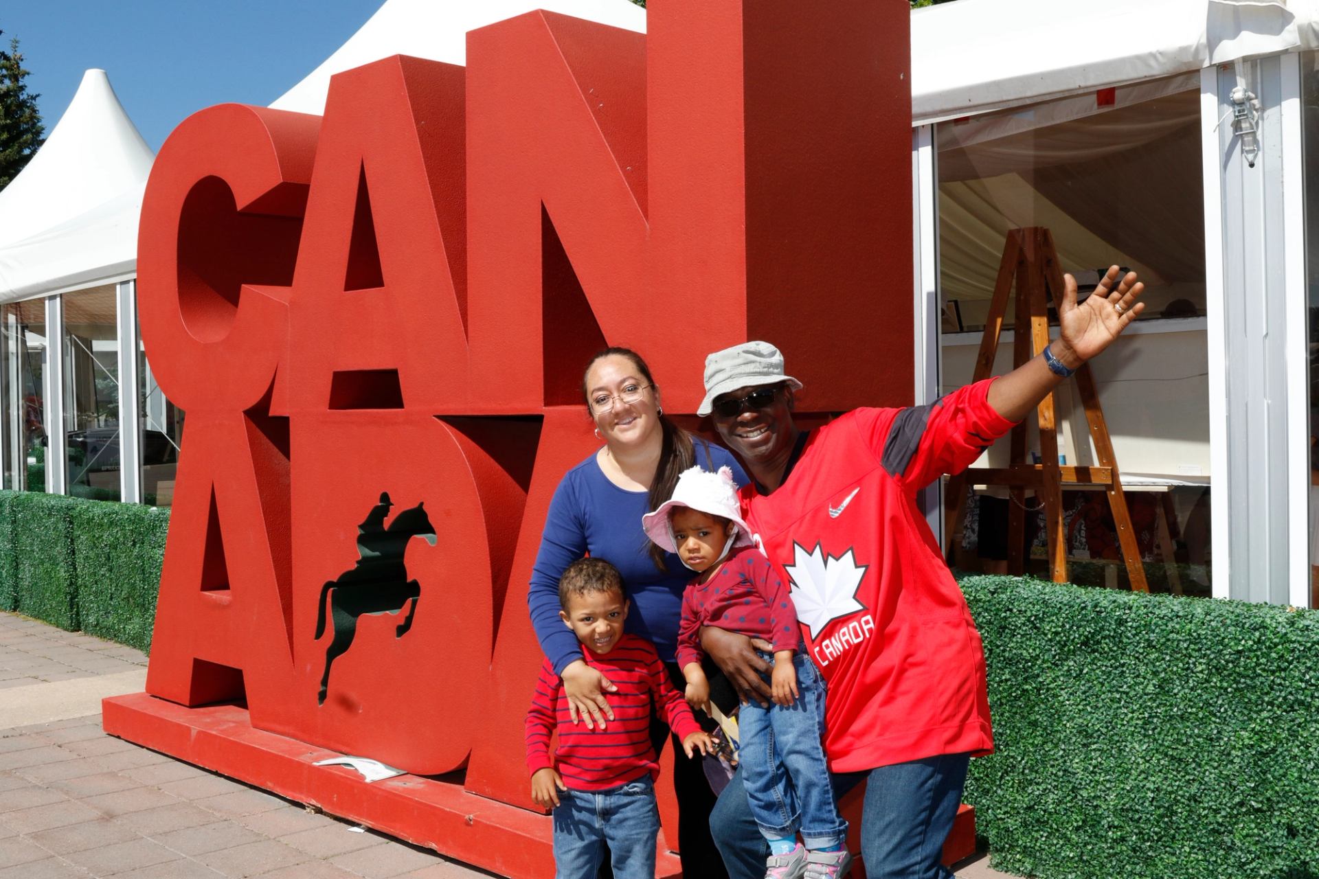 Family posing in front of a large red Canada Day display sign