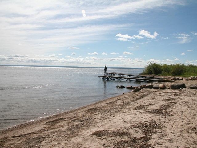 A person standing on a pier jutting out into Lesser Slave Lake.