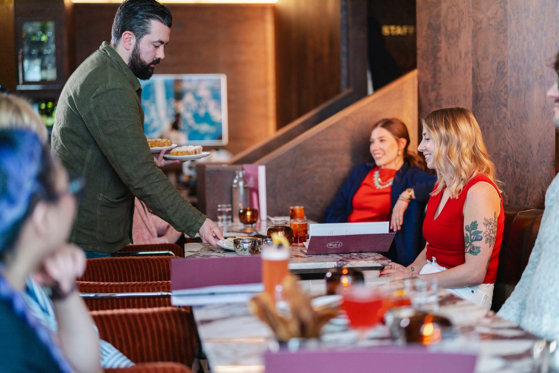 Serving food and beverages to a guest at Bar Henry.