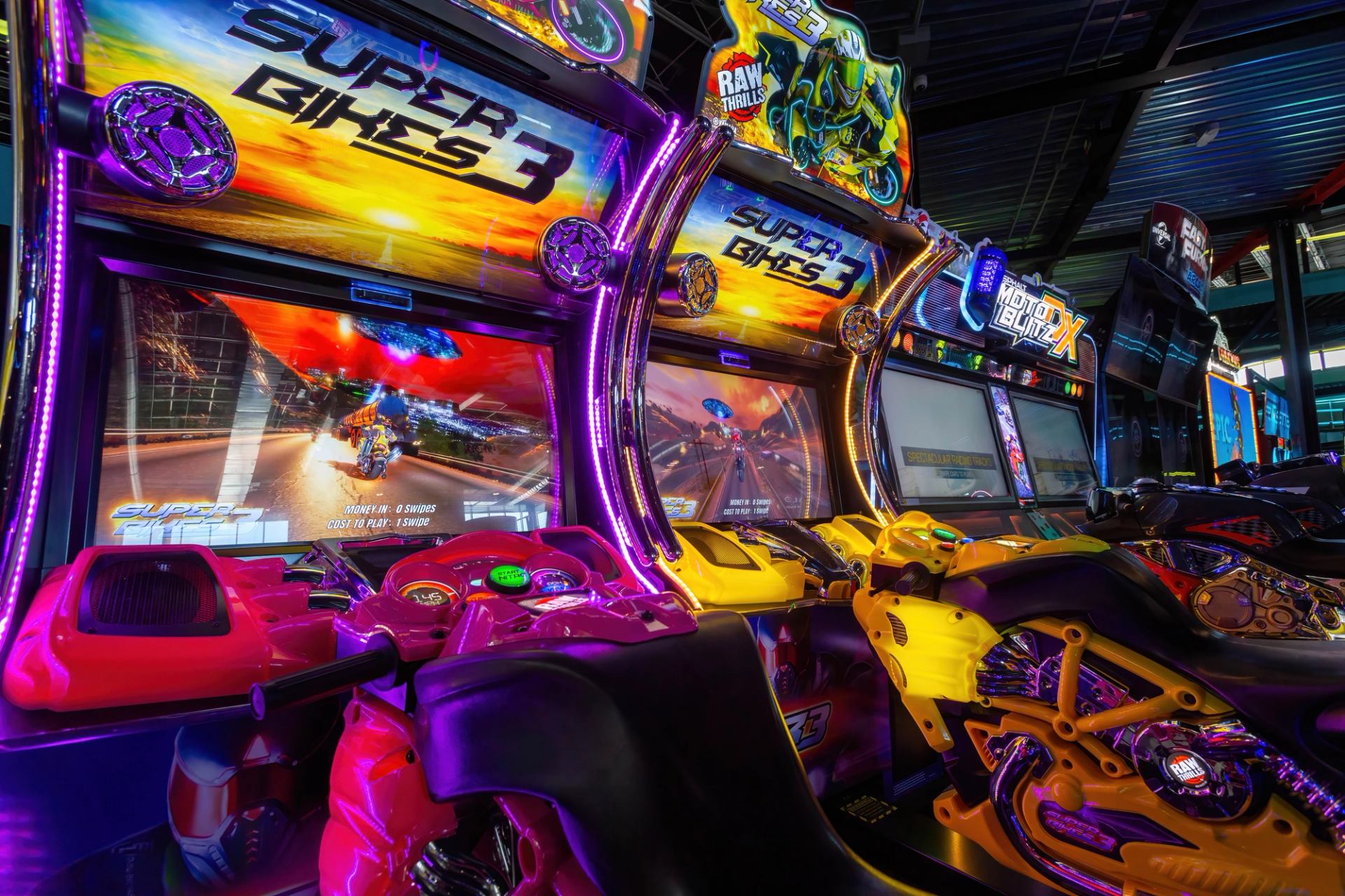 Bright arcade setup featuring colorful motorcycle racing games at Speeders entertainment center.