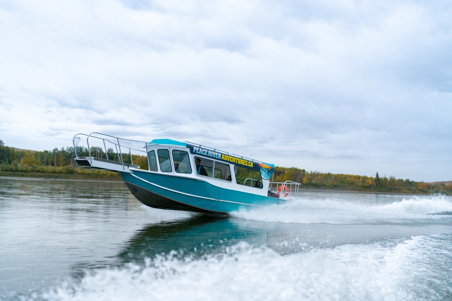 A blue boat cruises swiftly across the peaceful river waters.