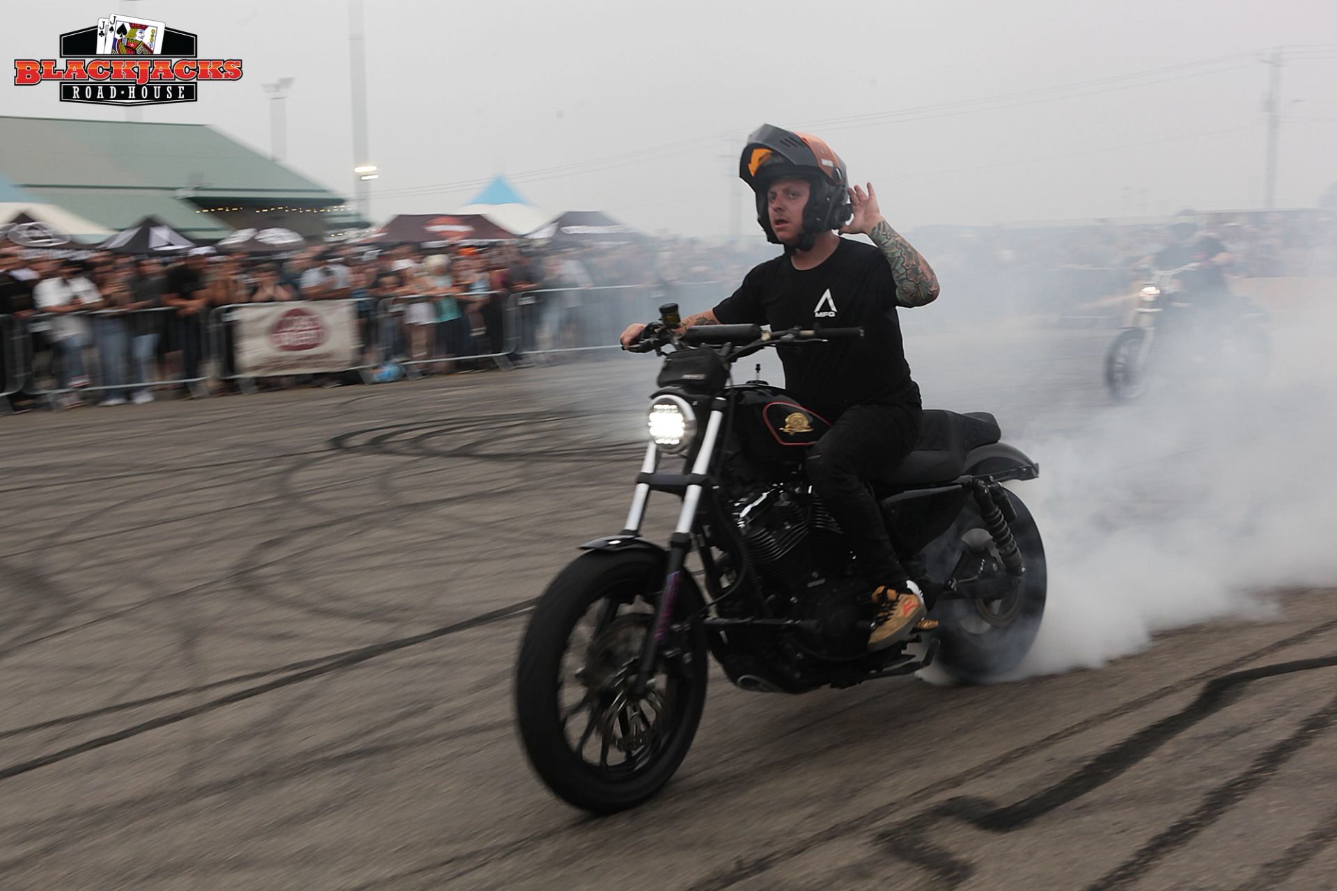 A biker smoking his tires with tire marks covering the payment.