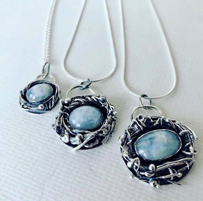 Silver necklaces with blue gemstones on a white fabric background.