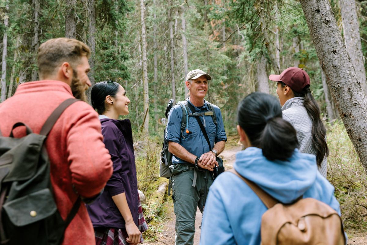 Group of hikers talk in forest during Lake Louise mountain adventure.