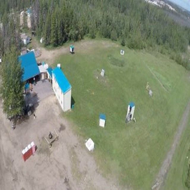 Aerial shot of blue-roofed buildings in a forested shooting range.
