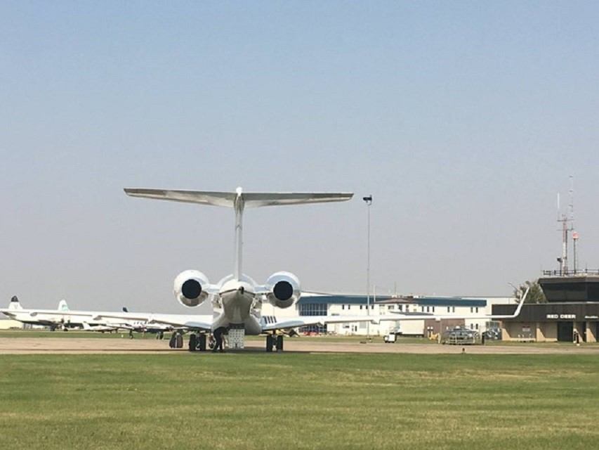 Jet seen from behind on runway at Red Deer Airport, terminal and planes in background.