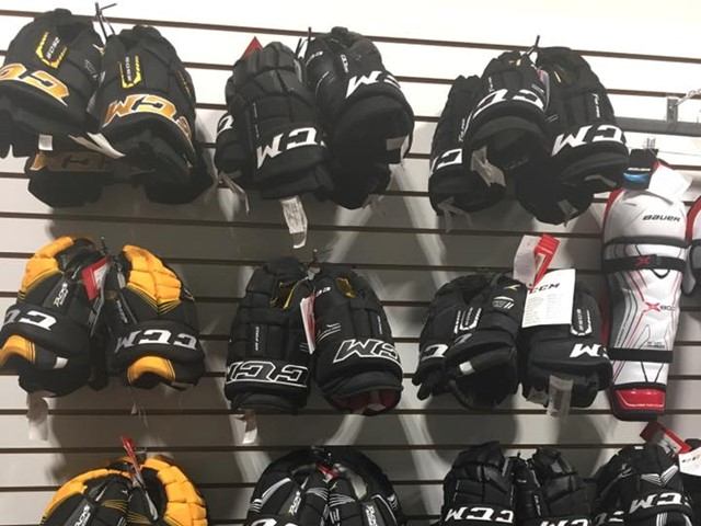 Hockey gloves and padded gear hanging on store display racks at Digger Sports.
